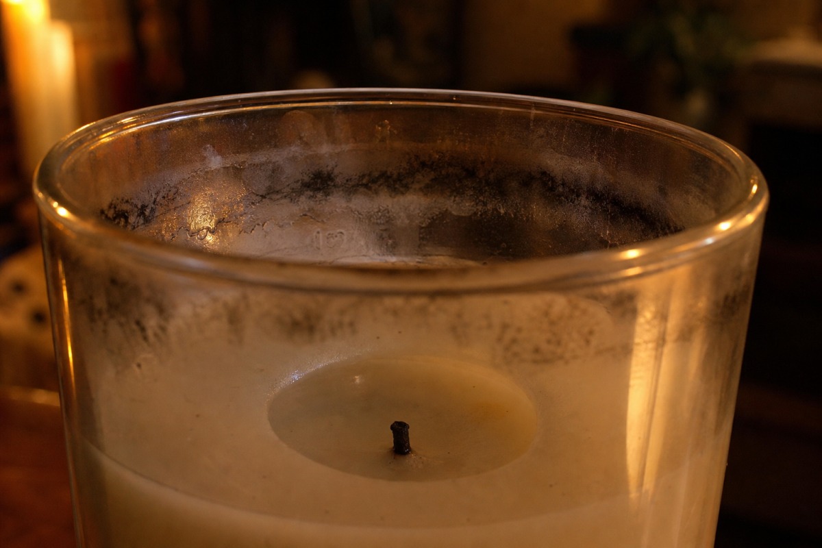 The inner wall of a glass candle with black greasy streaks of soot across the upper third