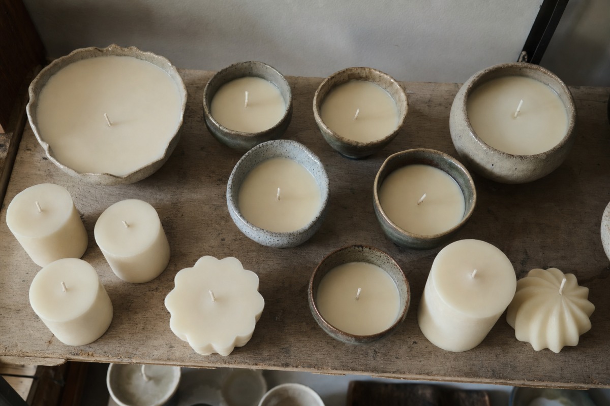 Freshly poured candles setting on a workshop shelf as they cure