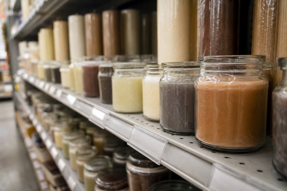 A row of cheap candles in plain glasses on a drugstore shelf